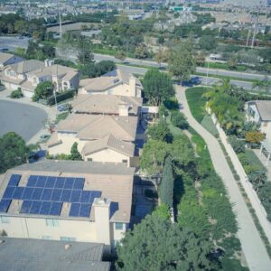 Aerial shot of suburban homes featuring solar panels and green landscapes.